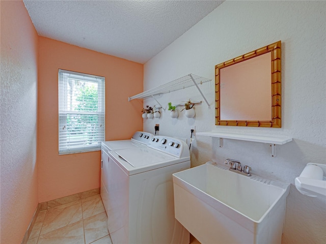 laundry room with washing machine and clothes dryer, a textured ceiling, light tile patterned flooring, and sink