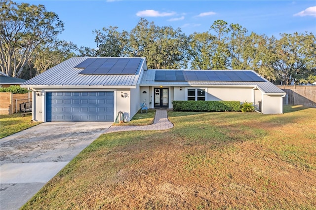 single story home featuring french doors, a front lawn, a garage, and solar panels