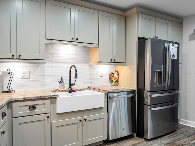 kitchen featuring sink, gray cabinets, appliances with stainless steel finishes, light stone counters, and wood-type flooring