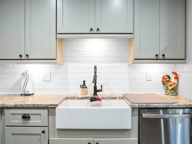 kitchen with light stone countertops, backsplash, stainless steel dishwasher, and sink