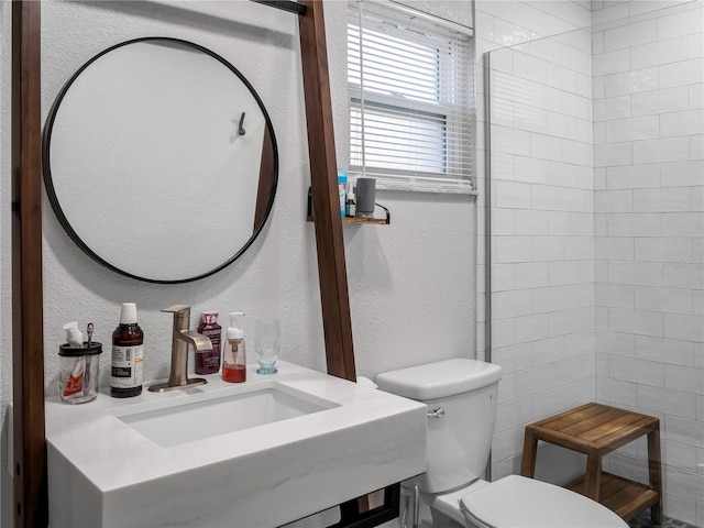 bathroom with toilet, sink, and tile walls