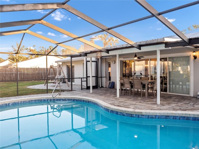 view of swimming pool featuring a patio, glass enclosure, and ceiling fan