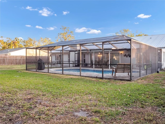 rear view of property with a lawn, glass enclosure, a patio area, and a fenced in pool