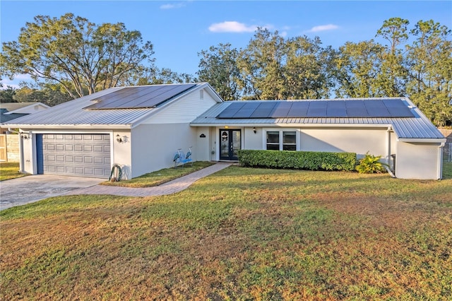 ranch-style home featuring solar panels, a front yard, and a garage