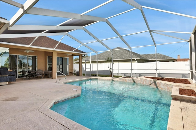 view of swimming pool featuring glass enclosure, ceiling fan, and a patio area