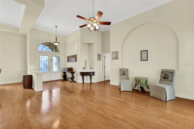 foyer featuring french doors, a towering ceiling, light hardwood / wood-style flooring, and crown molding