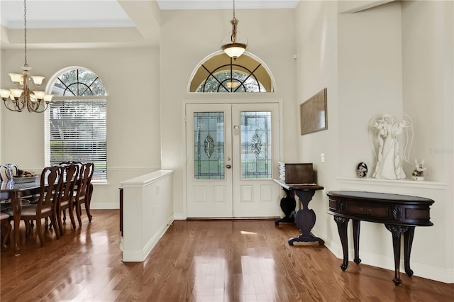 entryway with crown molding, hardwood / wood-style floors, french doors, and a notable chandelier