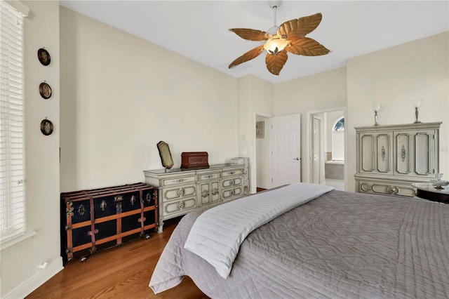 bedroom with multiple windows, ceiling fan, ensuite bath, and hardwood / wood-style flooring