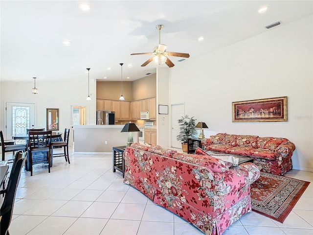 living room featuring ceiling fan, light tile patterned floors, and a high ceiling