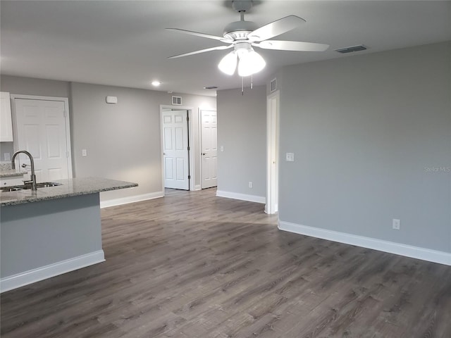 unfurnished living room featuring ceiling fan, dark hardwood / wood-style flooring, and sink