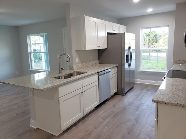 kitchen with white cabinets, a healthy amount of sunlight, light stone counters, and stainless steel appliances