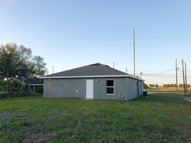 rear view of property with cooling unit and a lawn