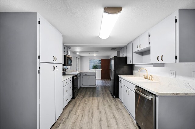 1891 18th St NW, Winter Haven, FL 33881 - kitchen with black appliances, light wood-style flooring, a peninsula, light countertops, and white cabinets