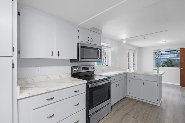 kitchen with sink, white cabinetry, appliances with stainless steel finishes, light hardwood / wood-style floors, and kitchen peninsula