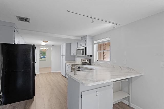 kitchen with kitchen peninsula, appliances with stainless steel finishes, light wood-type flooring, track lighting, and white cabinets