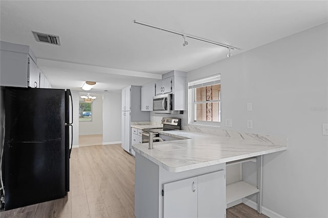 1891 18th St NW, Winter Haven, FL 33881 - kitchen with appliances with stainless steel finishes, track lighting, a peninsula, and light countertops