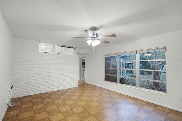 empty room with ceiling fan, brick wall, and light parquet flooring