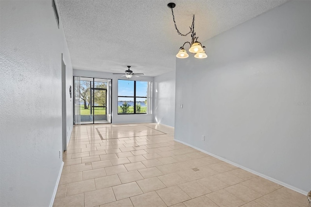 spare room with ceiling fan with notable chandelier, light tile patterned floors, and a textured ceiling