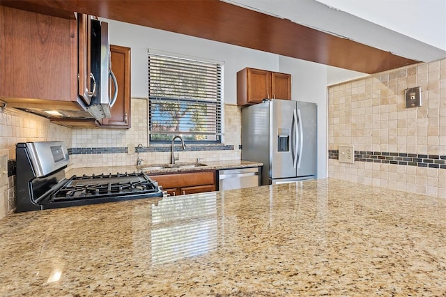 kitchen with decorative backsplash, light stone counters, sink, and appliances with stainless steel finishes