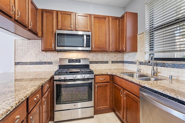 kitchen featuring decorative backsplash, light stone counters, sink, and stainless steel appliances