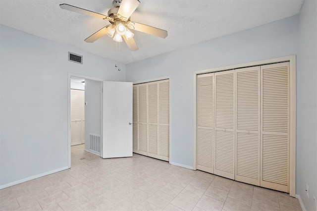 unfurnished bedroom featuring multiple closets, ceiling fan, and a textured ceiling