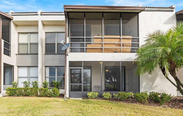 rear view of property featuring a lawn and a balcony