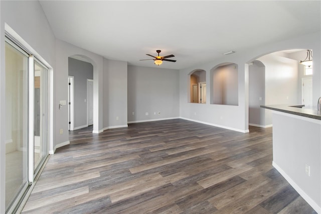 unfurnished living room with ceiling fan and dark wood-type flooring