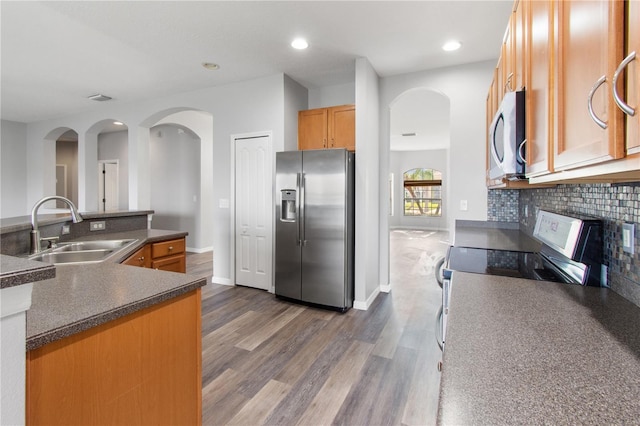 kitchen with dark wood-type flooring, decorative backsplash, sink, and stainless steel appliances