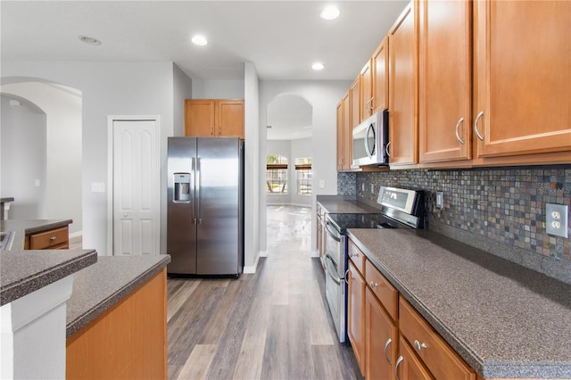 kitchen featuring backsplash, wood-type flooring, and stainless steel appliances