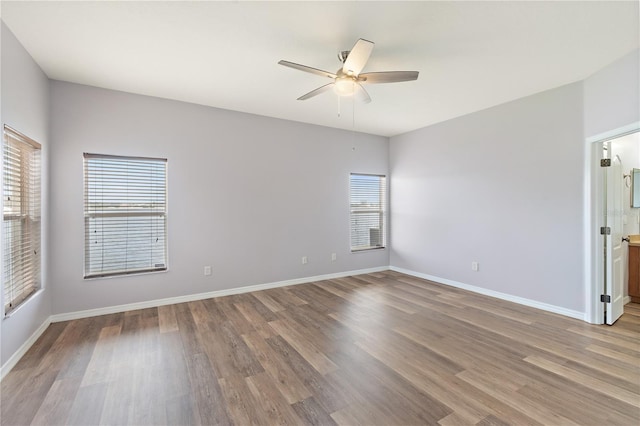 unfurnished room featuring ceiling fan, wood-type flooring, and a wealth of natural light