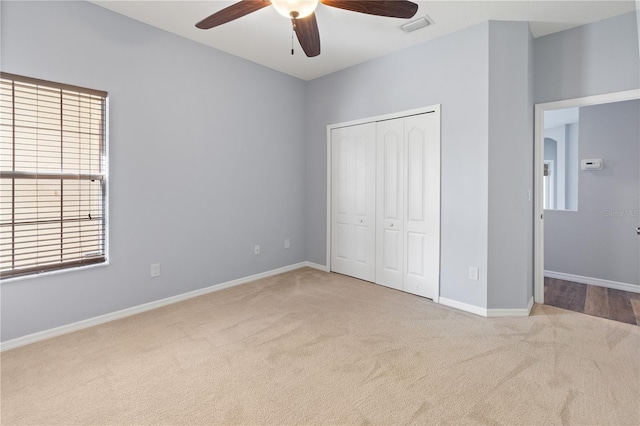 unfurnished bedroom with ceiling fan, light carpet, and a closet