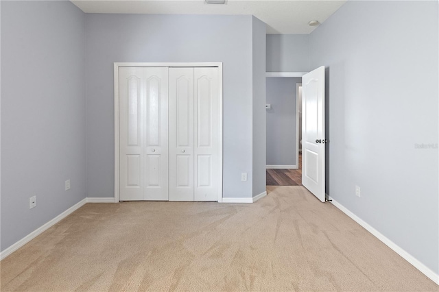 unfurnished bedroom with light carpet and a closet