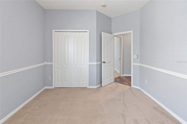 unfurnished bedroom featuring a closet and light colored carpet