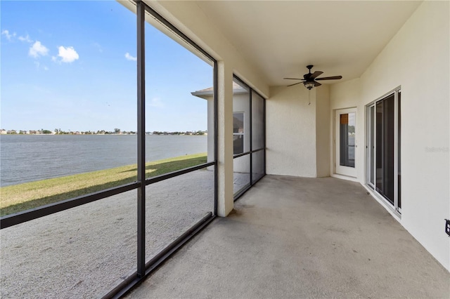 unfurnished sunroom featuring ceiling fan and a water view