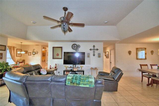 tiled living room featuring ceiling fan with notable chandelier and lofted ceiling