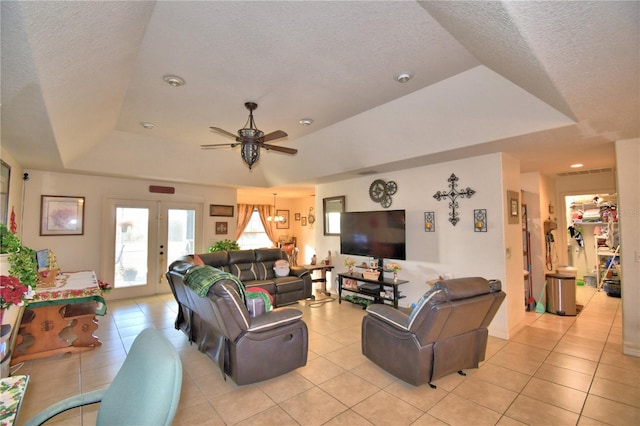 tiled living room with ceiling fan, a raised ceiling, a textured ceiling, and french doors