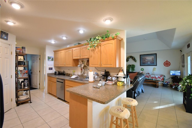 kitchen with stainless steel dishwasher, light tile patterned floors, light brown cabinetry, kitchen peninsula, and a breakfast bar area