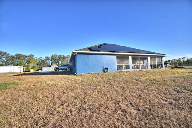 rear view of property with solar panels, a yard, and a sunroom