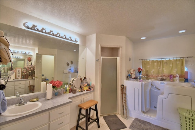 bathroom featuring tile patterned floors, washer / clothes dryer, a textured ceiling, vanity, and independent shower and bath