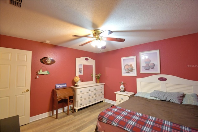 bedroom featuring ceiling fan, light hardwood / wood-style floors, and a textured ceiling