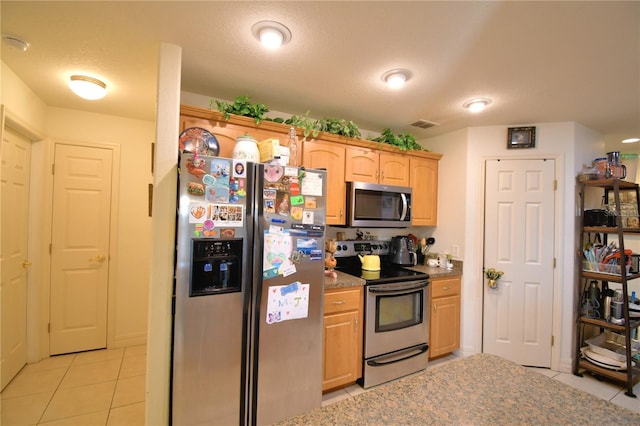 kitchen featuring a textured ceiling, light brown cabinets, light tile patterned floors, and stainless steel appliances