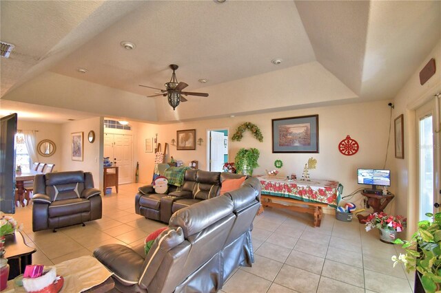 living room with ceiling fan, a healthy amount of sunlight, light tile patterned floors, and a tray ceiling