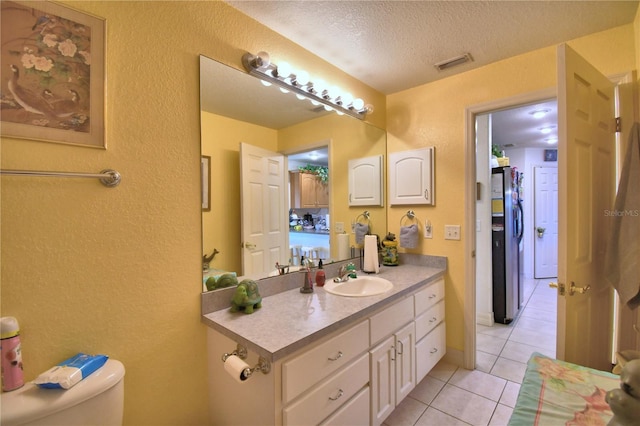 bathroom featuring tile patterned flooring, vanity, toilet, and a textured ceiling