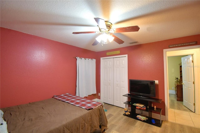 bedroom featuring ceiling fan, light hardwood / wood-style floors, a textured ceiling, and a closet