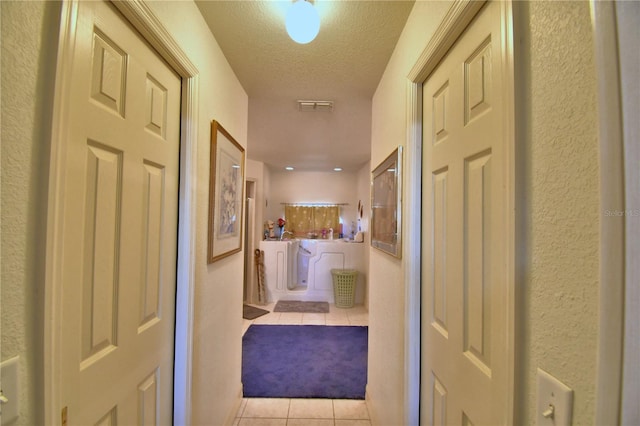 hallway with light tile patterned floors and a textured ceiling