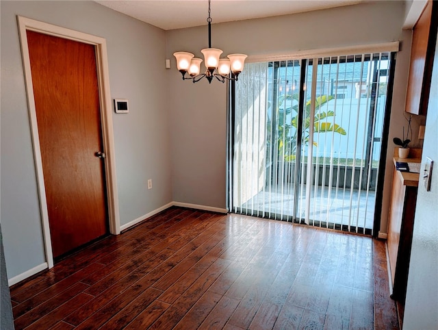 spare room featuring a notable chandelier, wood finished floors, and baseboards