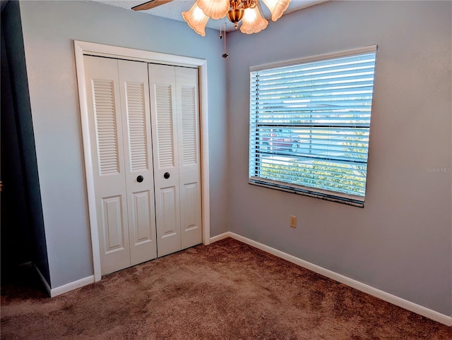 unfurnished bedroom with a closet, carpet, a ceiling fan, and baseboards