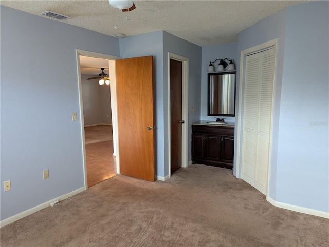 interior space featuring carpet, visible vents, a sink, and a textured ceiling