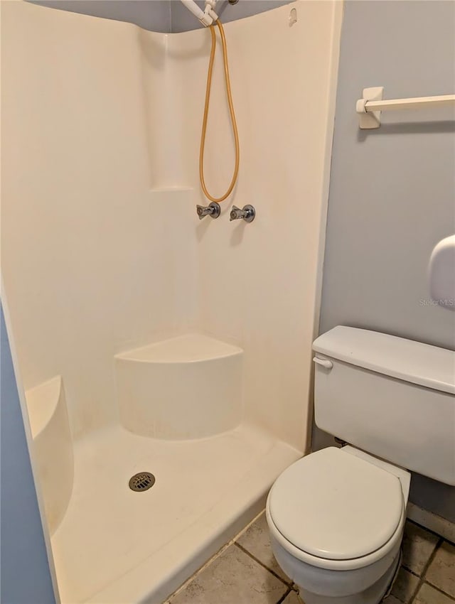 bathroom featuring toilet, a shower stall, and tile patterned floors