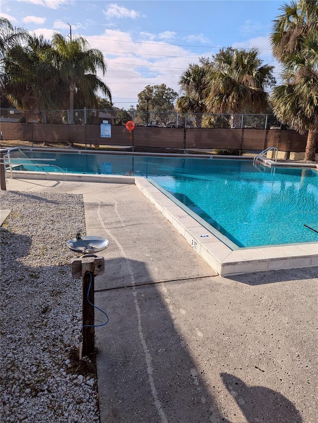 pool with a patio area and fence